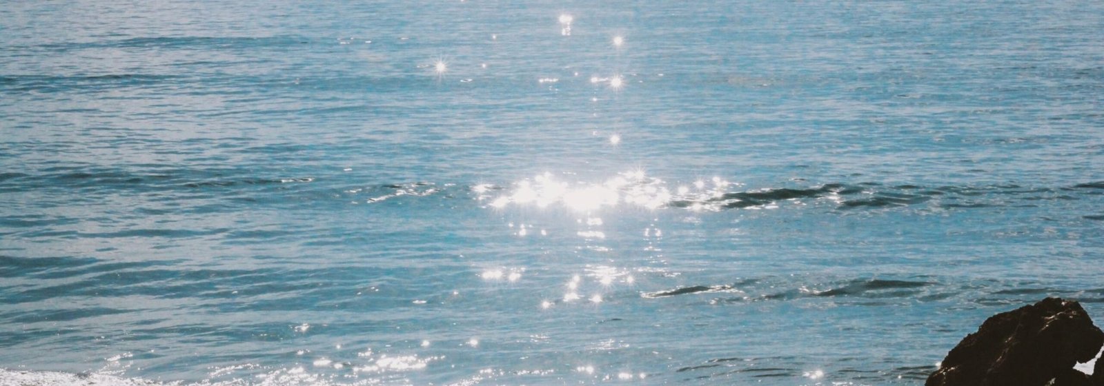 Tranquil beach scene with sparkling sea and sunny sky, perfect for summer relaxation.